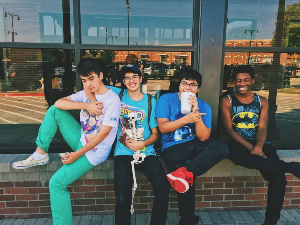 Un groupe d’élèves du secondaire assis devant leur école
